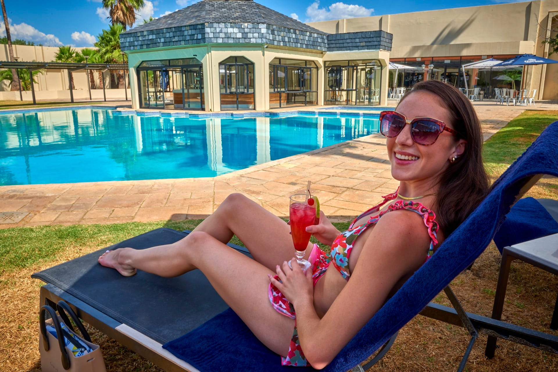 Woman relaxing on a poolside lounger with a cocktail at Mmabatho Palms, Mahikeng